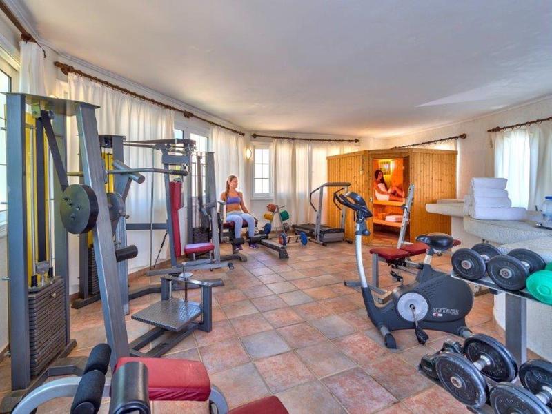 Lichte sportschool met diverse fitnessapparatuur en grote ramen.