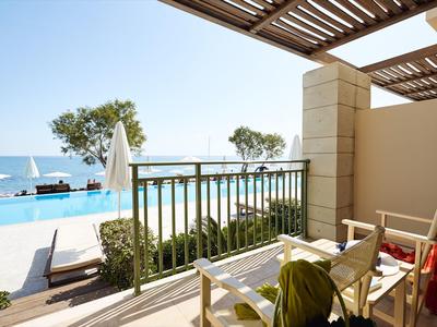 Balcone con sedie che si affaccia sulla piscina e sul mare in un hotel.