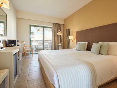 Modernes Hotelzimmer mit Doppelbett, Schreibtisch und Balkon mit Blick nach draußen.