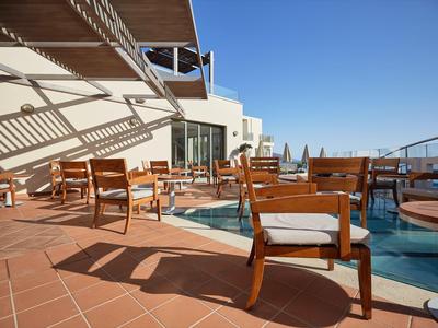 Hotelterrasse mit Holzstühlen und kleinem Pool unter klarem blauem Himmel