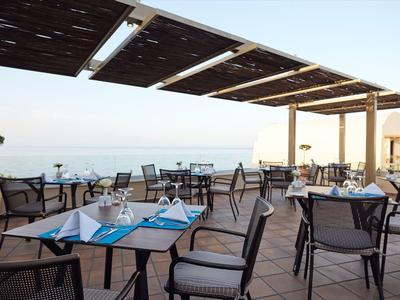Terrasse mit gedeckten Tischen und Blick aufs Meer bei klarem Himmel