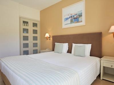 Camera d'hotel moderna con letto matrimoniale grande, comodini e illuminazione a parete elegante.