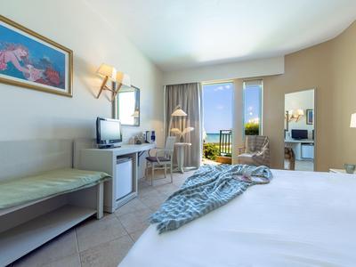 Habitación de hotel luminosa con cama doble, escritorio y balcón con vistas a paisaje montañoso.
