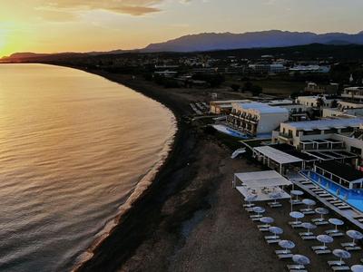 Atardecer sobre una larga playa con hoteles y una piscina en primer plano.
