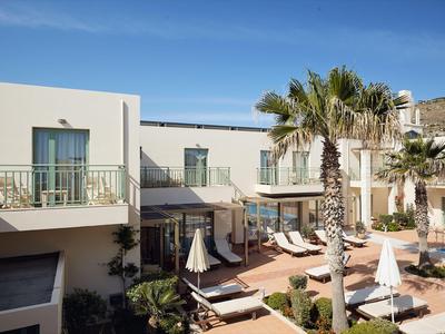 Complejo hotelero moderno con piscina, tumbonas y palmeras bajo un cielo azul claro.