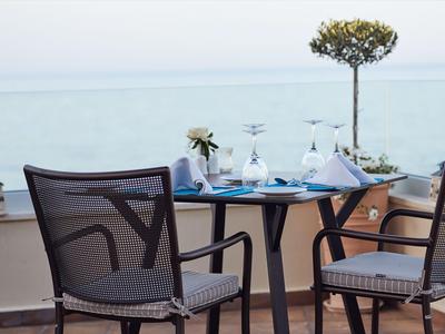 Dos sillas y una mesa con vasos en una terraza con vista al mar.