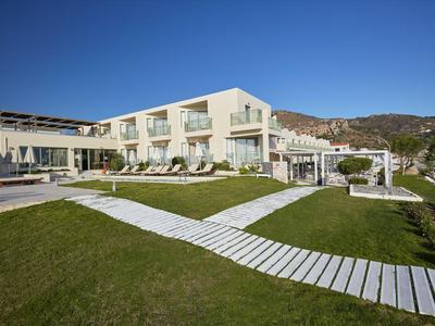 Hotel moderno con terraza soleada, tumbonas y vistas a las montañas bajo cielo despejado.