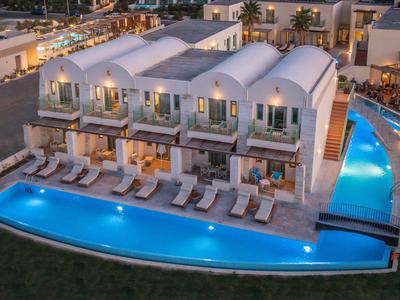 Complejo hotelero moderno con edificios blancos curvos y piscina exterior iluminada.