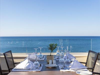 Mesa elegantemente puesta con vista al mar en una terraza de hotel bajo un cielo despejado.