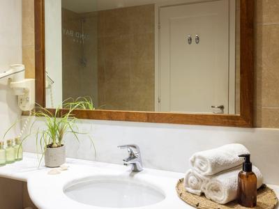 Baño moderno con lavabo, espejo grande y toallas dobladas.