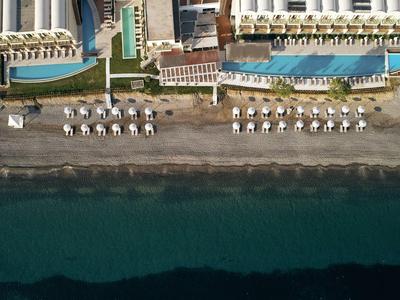 Zona de playa con tumbonas y dos hoteles justo al lado del agua.