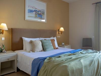 Habitación de hotel acogedora con cama doble, ropa de cama azul y verde y lámparas de noche.