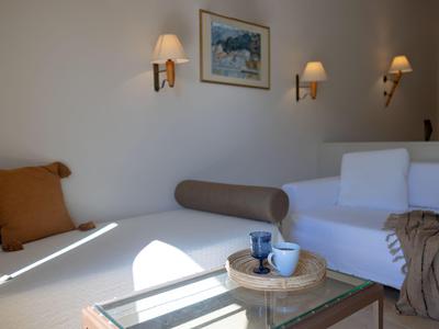 Salón de hotel luminoso con sofás blancos y marrones, lámparas de pared y cuadro enmarcado.