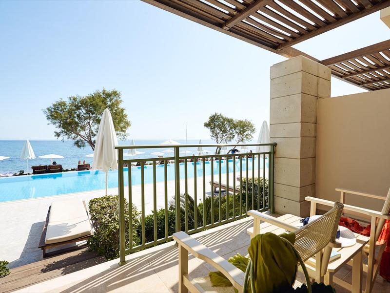 Balcone con sedie che si affaccia sulla piscina e sul mare in un hotel.