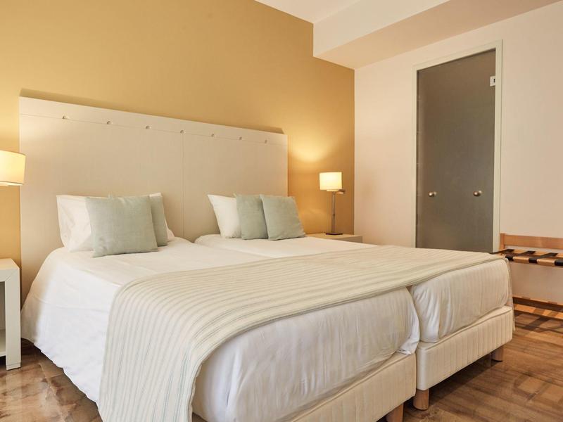 Due letti singoli in una camera d'hotel luminosa e accogliente con comodini e lampade.