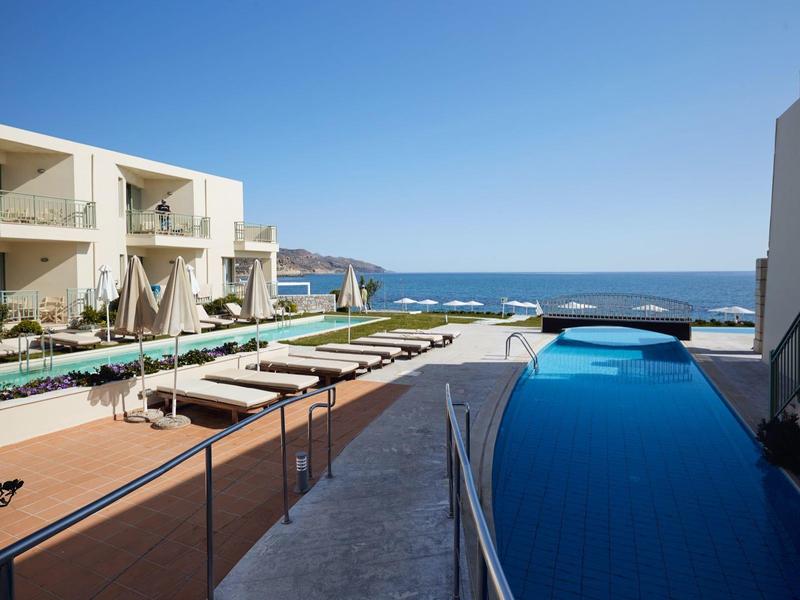 Area piscina moderna con lettini e vista mare sotto un cielo azzurro limpido.