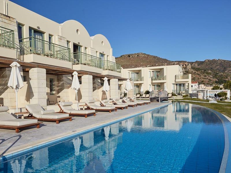 Piscina moderna dell'hotel con lettini e vista sulle montagne sotto un cielo limpido.