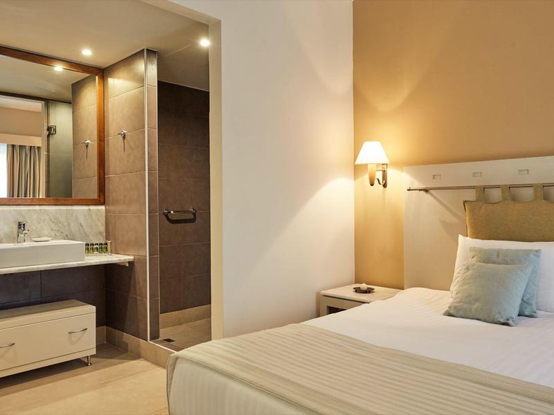 Camera d'hotel moderna con letto, comodino e area bagno con lavabo.