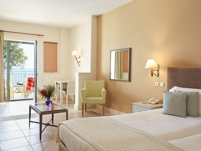 Camera d'hotel luminosa con balcone e vista sul mare.