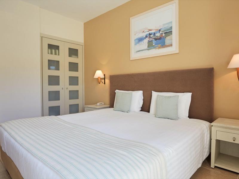 Camera d'hotel moderna con letto matrimoniale grande, comodini e illuminazione a parete elegante.