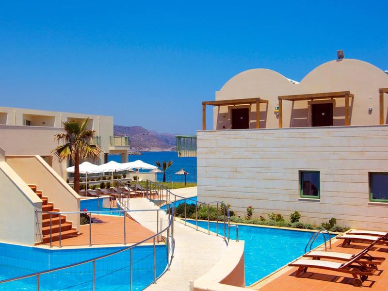 Hotel con piscina all'aperto, lettini e vista sul mare sotto un cielo azzurro