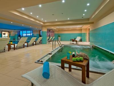 Área moderna de piscina interior con tumbonas, paredes azul-verde y zona de relajación.