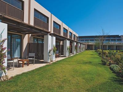 Moderner Hotelkomplex mit Terrasse, Stühlen und gepflegtem Gras bei klarem Himmel