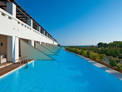 Piscina moderna en un hotel con vista a la naturaleza y cielo azul despejado.