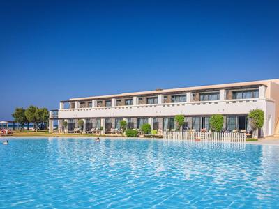 Complejo hotelero moderno con gran piscina bajo un cielo azul claro.