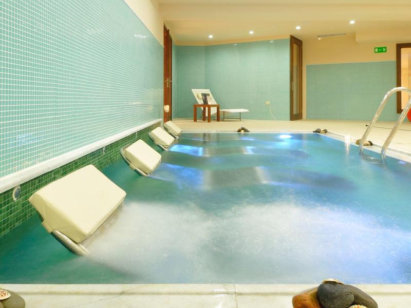 Piscina interior moderna con tumbonas y luz tenue en área de relajación de hotel