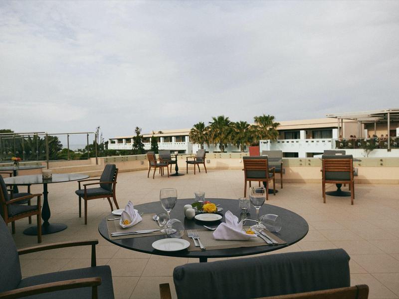 Área al aire libre de un hotel con mesas y sillas bajo un cielo nublado.