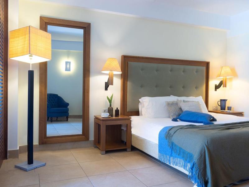 Habitación de hotel moderna con cama doble, espejo grande, lámparas de noche y lámpara de pie.