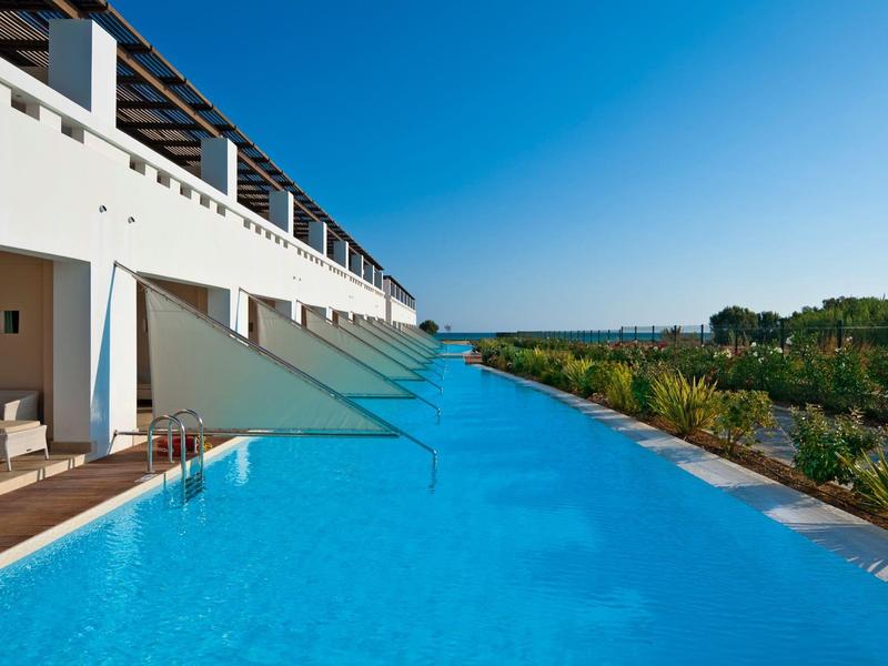 Piscina moderna en un hotel con vista a la naturaleza y cielo azul despejado.