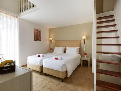 Modernes Hotelzimmer mit zwei Einzelbetten, Holzboden, Treppe und natürlichem Licht von Fenster.