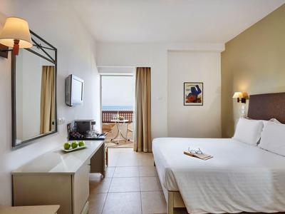 Modernes Hotelzimmer mit großem Bett, Schreibtisch, Fernseher und Balkon mit Blick.