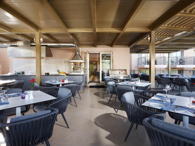 Área exterior cubierta de un restaurante de hotel con mesas y sillas para comer.