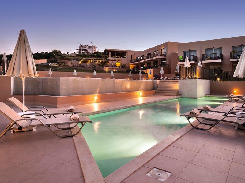 Piscina exterior moderna con tumbonas y sombrillas en un hotel al atardecer.