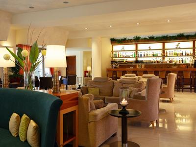 Einladender Hotel-Loungebereich mit gemütlichen Sesseln, Bar im Hintergrund und gedämpfter Beleuchtung.