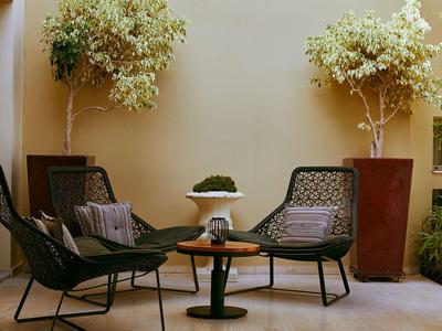 Gemütliche Outdoor-Lounge mit zwei schwarzen Stühlen, Tisch und Pflanzen in Töpfen.