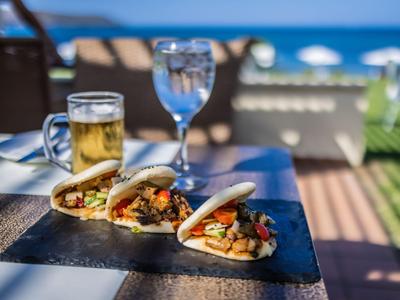 Drei asiatische Bao-Brötchen auf einem Tisch mit einem Bier und einem Getränk im Hintergrund am Strandhotel.