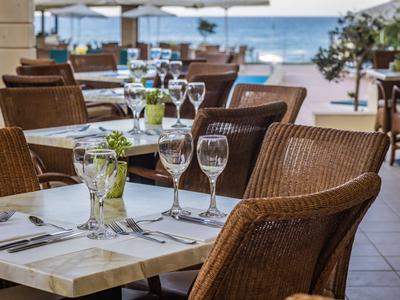 Hotelterrasse mit gedeckten Tischen und Blick auf das Meer im Hintergrund.