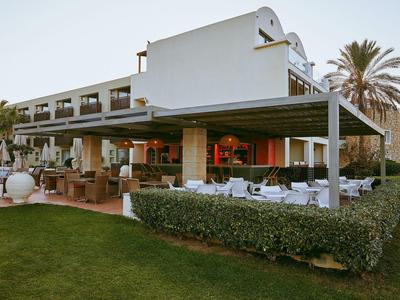Modernes Hotel mit großzügiger Terrasse und gepflegtem Garten bei Dämmerung.
