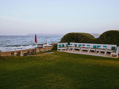 Moderner Außenbereich mit weißen Sitzbänken und Blick auf das Meer bei ruhigem Wetter.