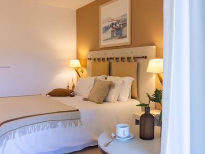 Gemütliches Hotelzimmer mit zwei Betten, warmen Farben und modernen Lampen.