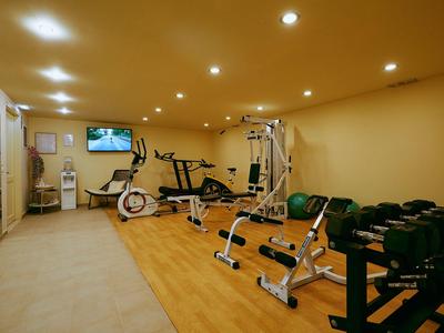 Helles Fitnessstudio mit Holzfußboden, Gewichten und verschiedenen Trainingsgeräten.