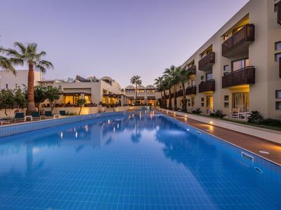 Moderner Hotelpool mit klarblauem Wasser und Palmendekor bei Abenddämmerung.