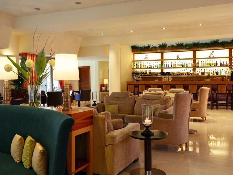 Gezellige hotellounge met fauteuils, barkrukken en warme verlichting.