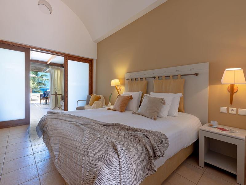 Knusse slaapkamer met groot bed, nachtkastjes, lampen en toegang tot een zonnig buitengebied.