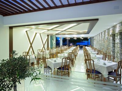 Großes, offenes Restaurant mit weißen Tischdecken und Holzstühlen bei Nacht.