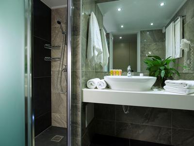 Moderne badkamer met wastafel, spiegel, handdoeken en douche met glazen deur.